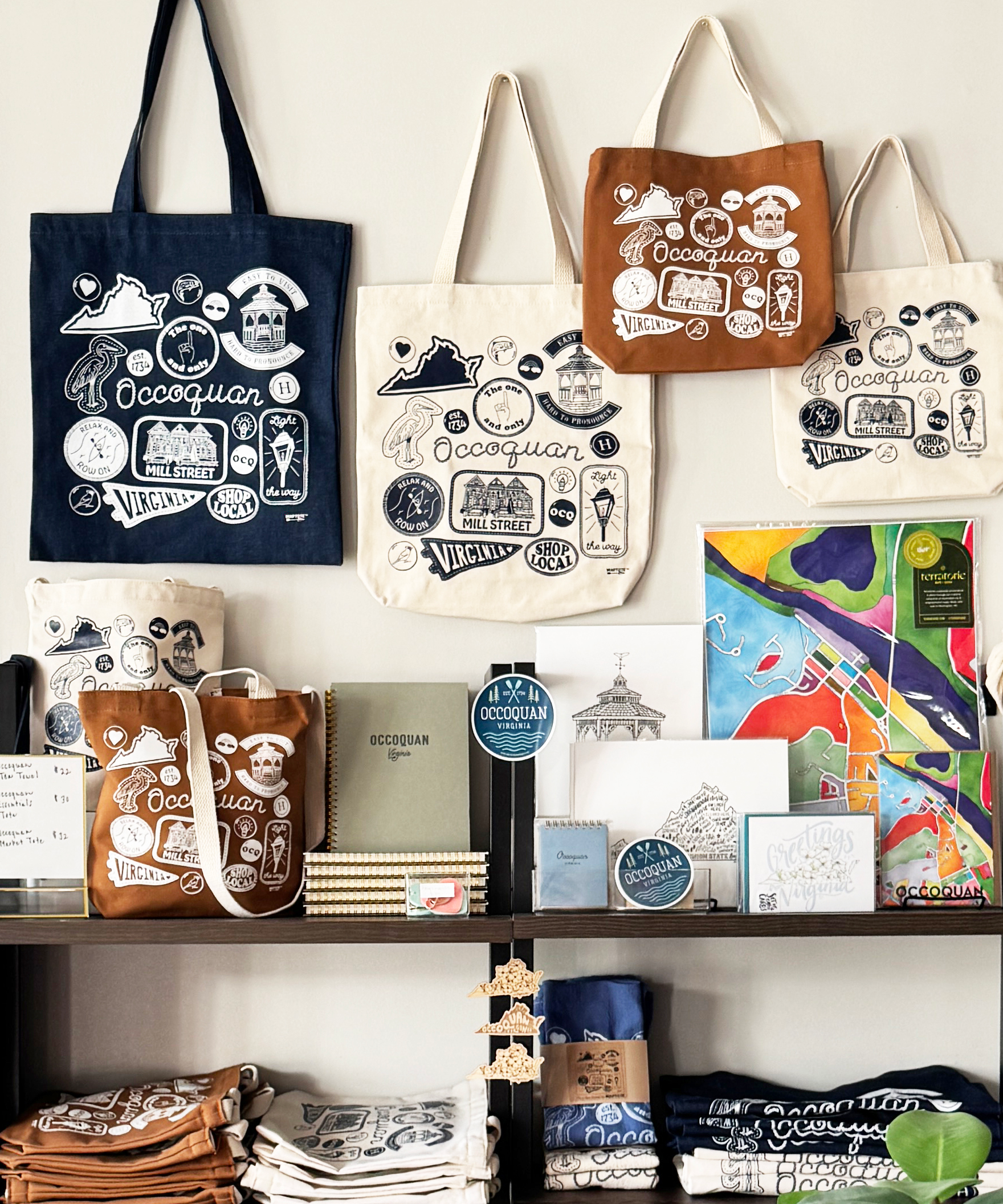 Collection of custom tote bags other merchandise on a shelf with a white background.